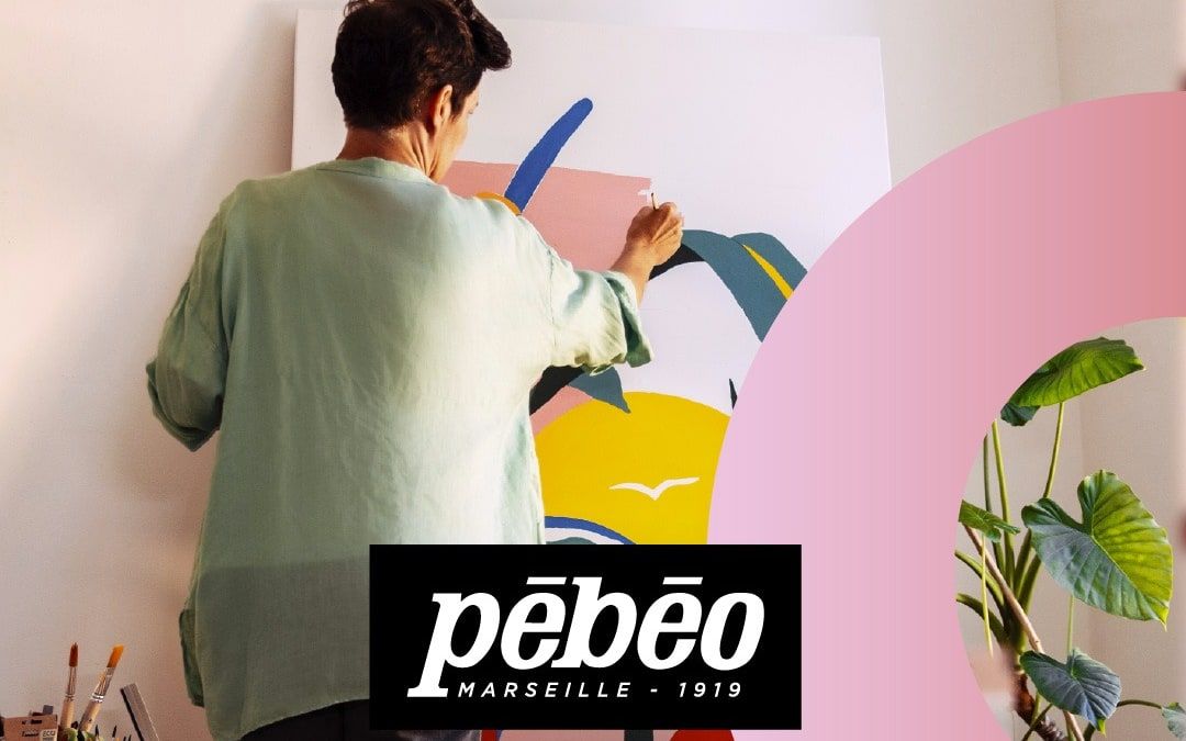 Une artiste peint une grande toile colorée, logo Pébéo au premier plan